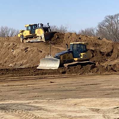Two bulldozers working a mound of dirt